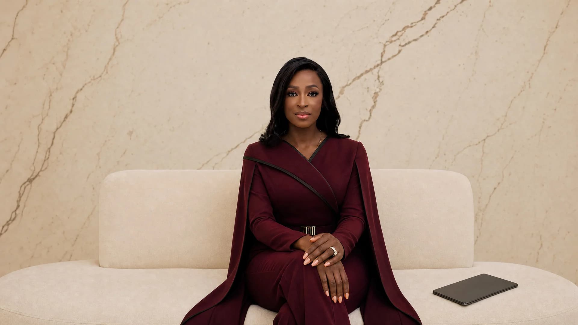 Ruth Kudzai seated in a burgundy cape suit